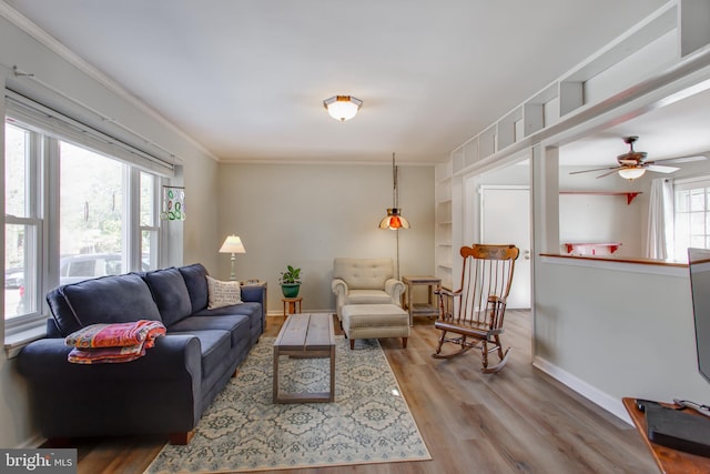 living room featuring hardwood / wood-style flooring, ornamental molding, and ceiling fan