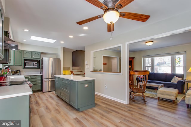 kitchen with green cabinetry, a skylight, light hardwood / wood-style flooring, ceiling fan, and stainless steel appliances