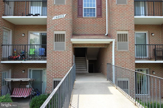 view of exterior entry featuring brick siding and a balcony