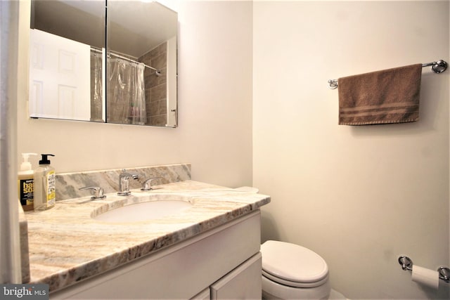 full bathroom featuring a shower with shower curtain, vanity, and toilet