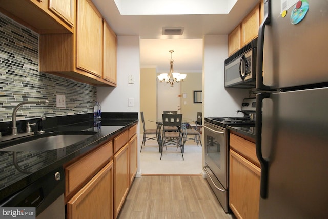 kitchen with stainless steel appliances, a sink, visible vents, backsplash, and light wood finished floors