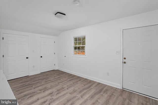 interior space featuring lofted ceiling, wood finished floors, and baseboards