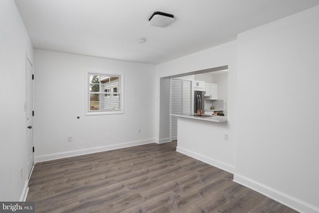 spare room with dark wood-style flooring and baseboards