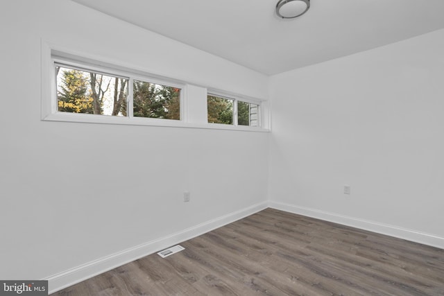 unfurnished room with visible vents, dark wood finished floors, and baseboards