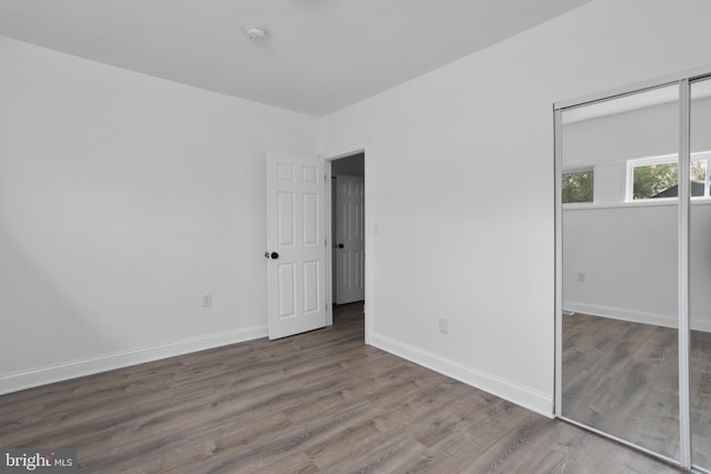 unfurnished bedroom featuring a closet, baseboards, and wood finished floors