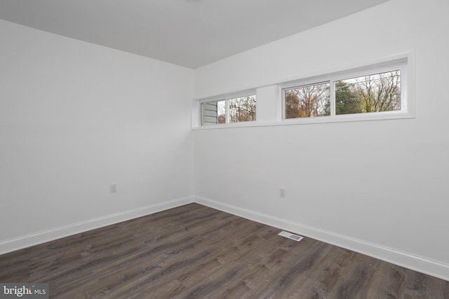 spare room featuring visible vents, dark wood finished floors, and baseboards