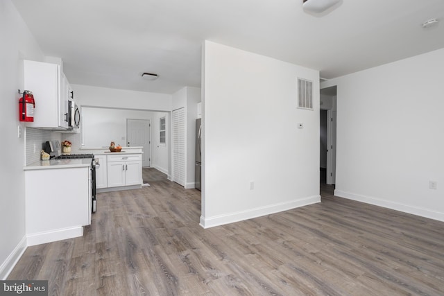 kitchen with visible vents, appliances with stainless steel finishes, wood finished floors, light countertops, and white cabinetry