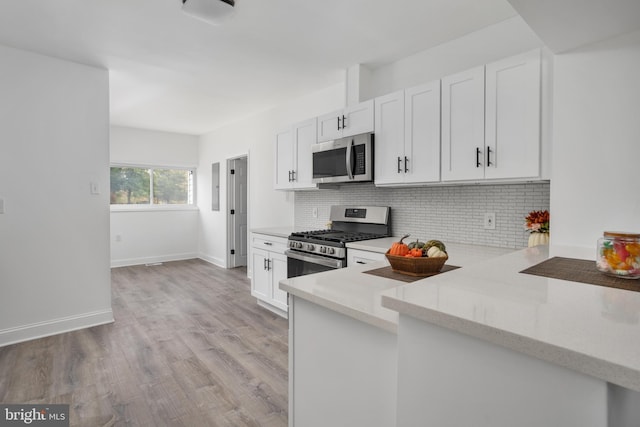 kitchen with stainless steel appliances, white cabinets, light wood-style flooring, and backsplash