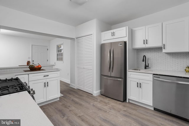 kitchen with a sink, white cabinetry, light countertops, appliances with stainless steel finishes, and light wood-type flooring