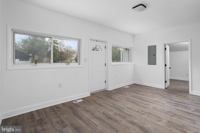 unfurnished room with baseboards, wood finished floors, visible vents, and electric panel