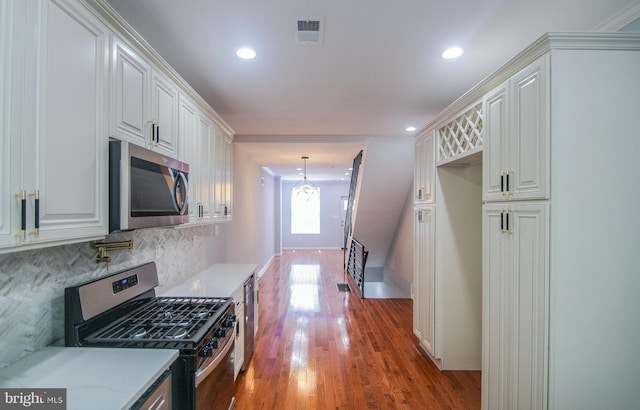 kitchen featuring appliances with stainless steel finishes, dark hardwood / wood-style flooring, hanging light fixtures, and white cabinets