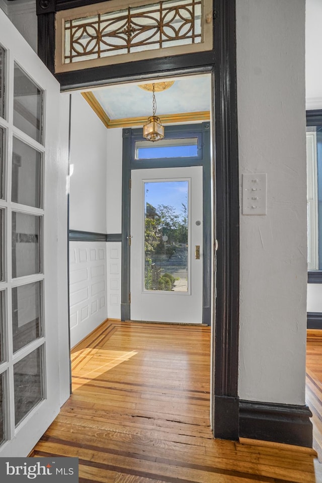 interior space featuring hardwood / wood-style flooring, crown molding, and an inviting chandelier