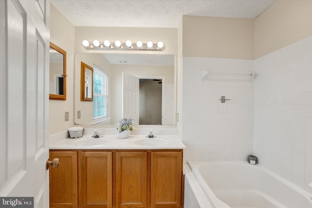 full bathroom featuring a textured ceiling, double vanity, tub / shower combination, and a sink