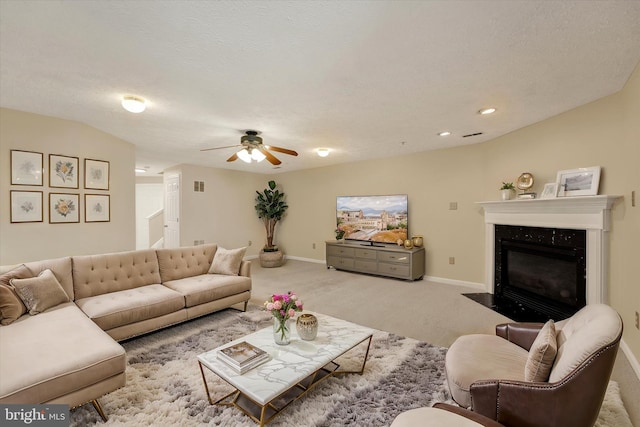 carpeted living area with visible vents, a fireplace with flush hearth, ceiling fan, a textured ceiling, and baseboards