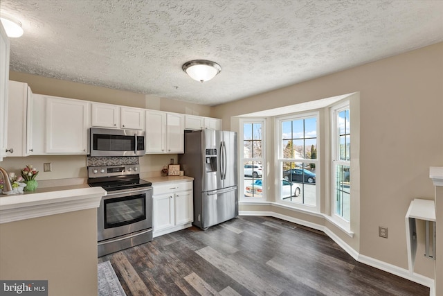 kitchen with white cabinetry, stainless steel appliances, dark wood finished floors, and light countertops