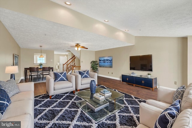 living area with baseboards, a textured ceiling, stairway, and wood finished floors