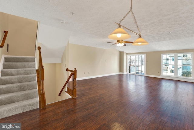 unfurnished living room featuring a textured ceiling, baseboards, and wood finished floors