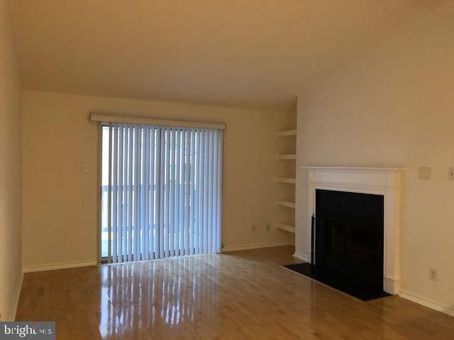 unfurnished living room with hardwood / wood-style floors and built in features