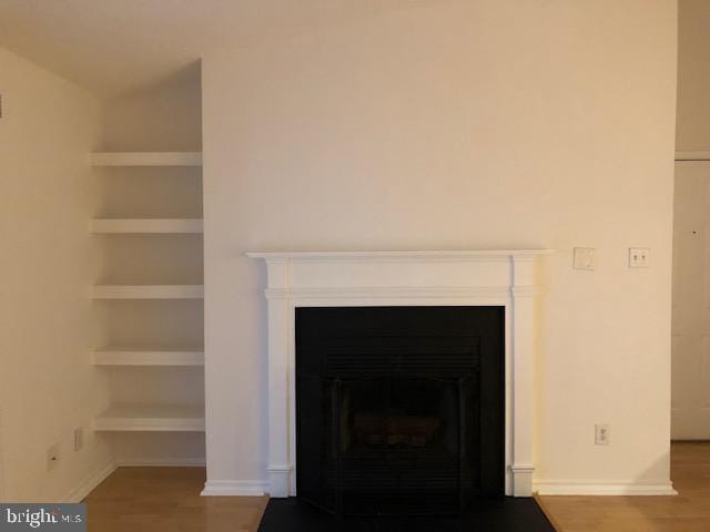 interior details featuring built in shelves and hardwood / wood-style floors