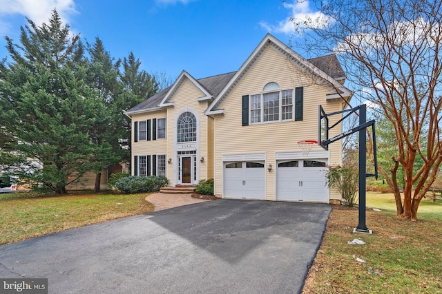 view of front of house featuring an attached garage, aphalt driveway, and a front yard