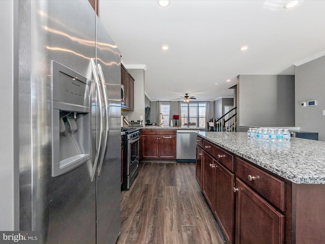 kitchen featuring appliances with stainless steel finishes, light stone counters, a center island, dark hardwood / wood-style flooring, and kitchen peninsula