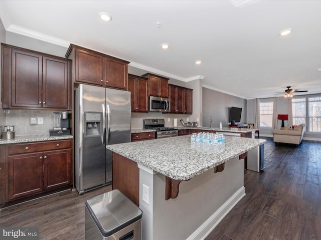 kitchen featuring a center island, appliances with stainless steel finishes, a breakfast bar area, and dark hardwood / wood-style floors