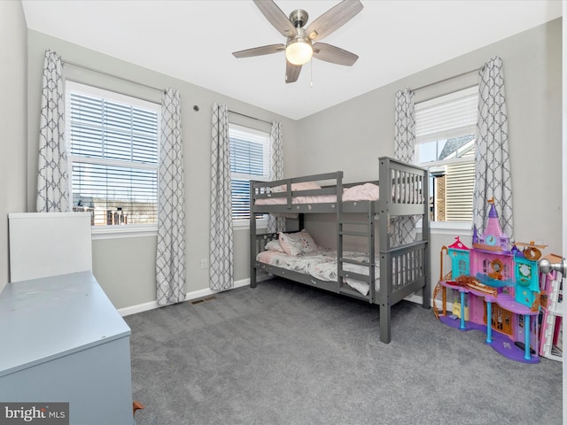 bedroom featuring ceiling fan, dark colored carpet, and multiple windows