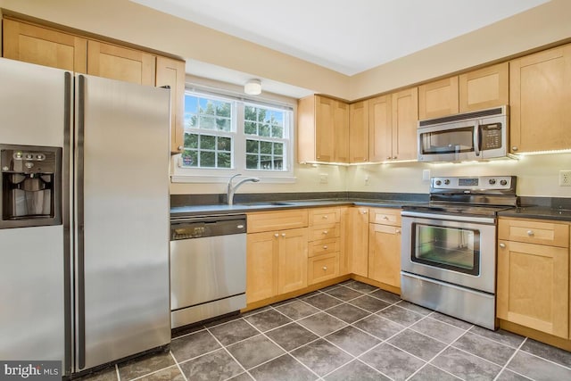 kitchen featuring light brown cabinetry, sink, dark tile patterned floors, and appliances with stainless steel finishes