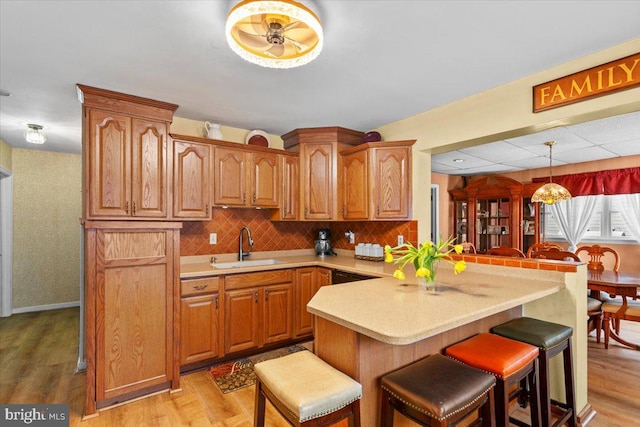 kitchen featuring sink, a breakfast bar area, light hardwood / wood-style floors, and decorative light fixtures