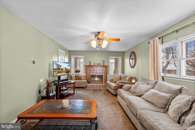 living room featuring ceiling fan, a tile fireplace, carpet flooring, and a wealth of natural light