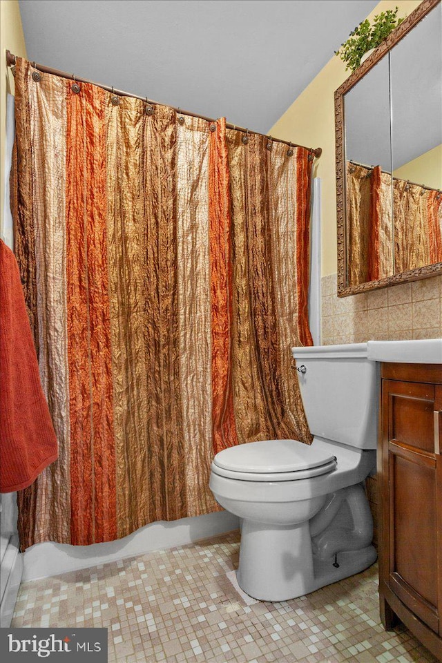 bathroom with toilet, tile patterned floors, tile walls, and vanity