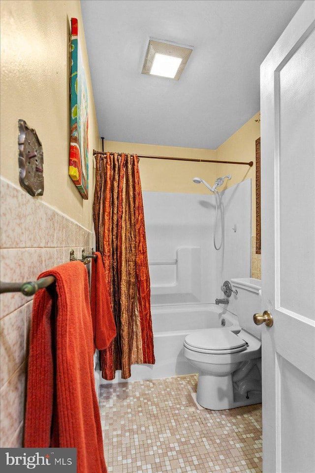 bathroom featuring tile patterned floors, tile walls, shower / tub combo with curtain, and toilet