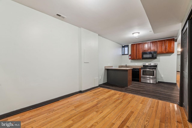 kitchen with dark hardwood / wood-style flooring, black appliances, and kitchen peninsula