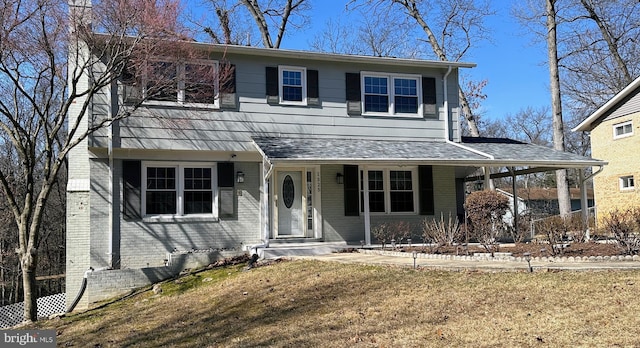 view of front of property featuring brick siding, a front lawn, and a shingled roof