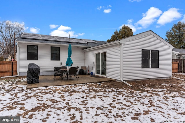 snow covered house featuring a patio and solar panels