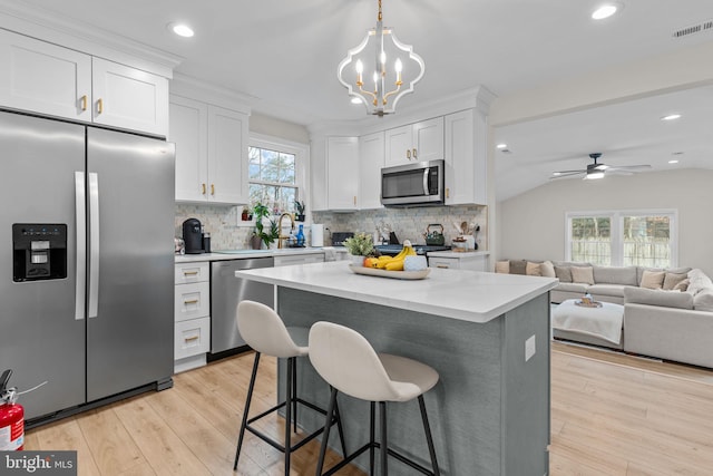 kitchen featuring tasteful backsplash, stainless steel appliances, light hardwood / wood-style floors, and white cabinets