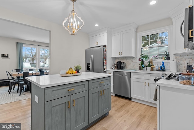 kitchen with a kitchen island, pendant lighting, white cabinetry, gray cabinetry, and stainless steel appliances