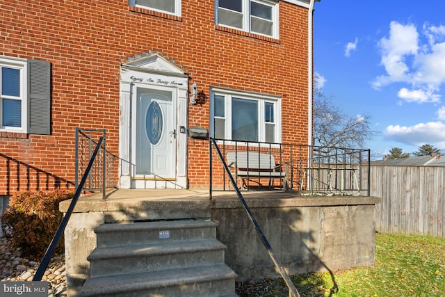 entrance to property with fence and brick siding