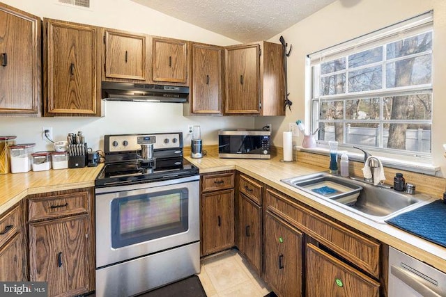 kitchen with a textured ceiling, under cabinet range hood, a sink, light countertops, and appliances with stainless steel finishes