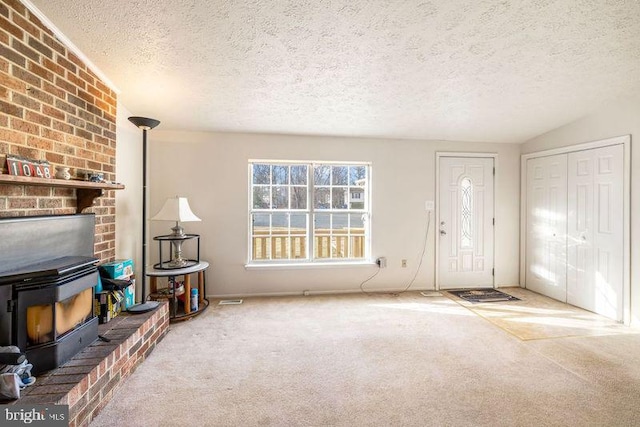 interior space with carpet floors, a wood stove, and a textured ceiling