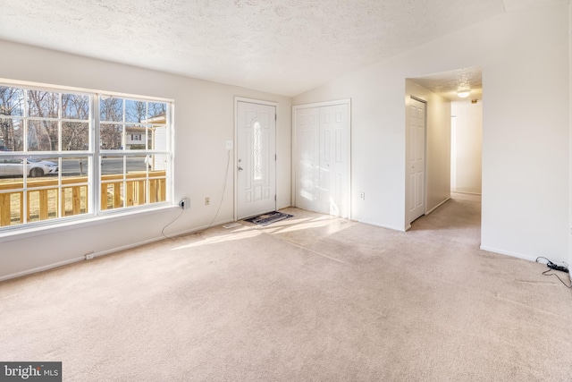 entrance foyer featuring lofted ceiling, light carpet, and a textured ceiling