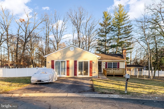 view of front of house featuring a front yard, fence, a chimney, and a wooden deck