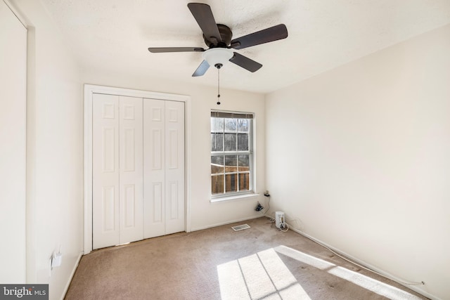 unfurnished bedroom featuring baseboards, visible vents, ceiling fan, carpet flooring, and a closet