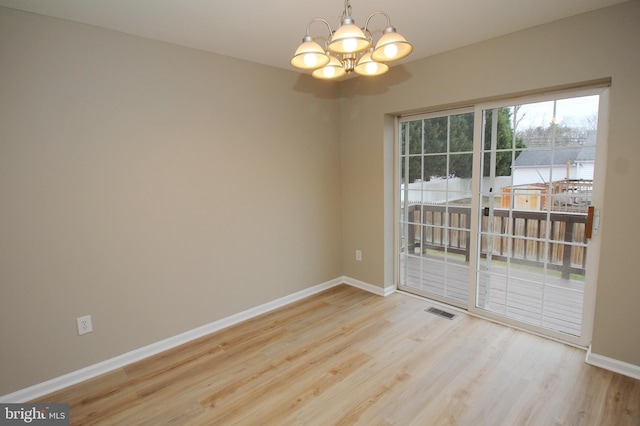 empty room with light hardwood / wood-style floors and a notable chandelier