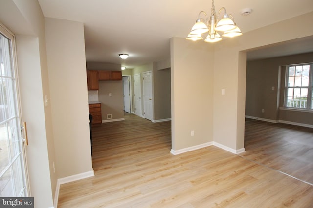 unfurnished dining area featuring a notable chandelier and light wood-type flooring