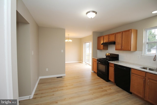 kitchen featuring sink, decorative light fixtures, light wood-type flooring, decorative backsplash, and black appliances