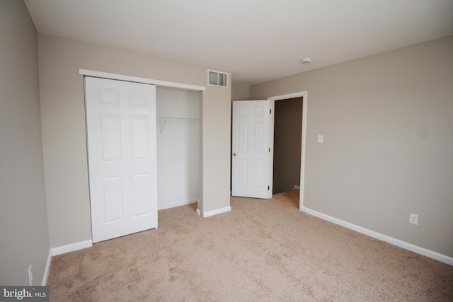 unfurnished bedroom featuring light colored carpet and a closet