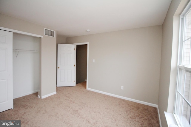 unfurnished bedroom with light carpet and a closet