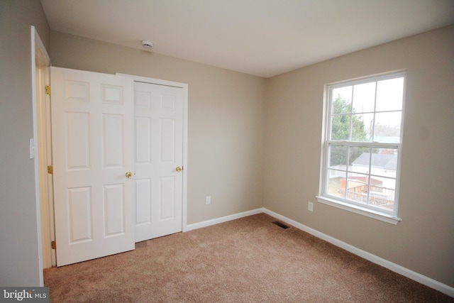 unfurnished bedroom featuring multiple windows and light colored carpet