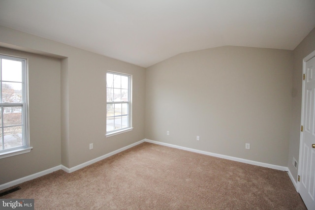 carpeted empty room with lofted ceiling